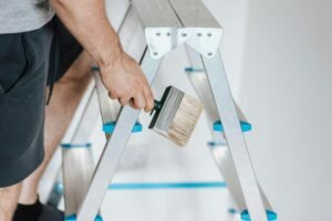 Painter with brush climbing ladder during renovation work